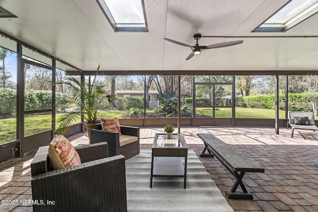 sunroom / solarium with a healthy amount of sunlight, a skylight, and a ceiling fan