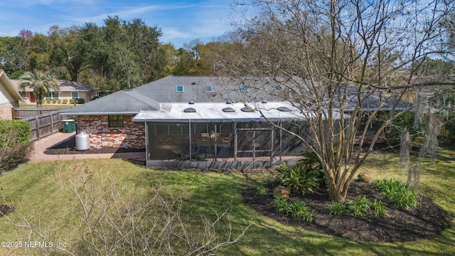 back of house with a yard, brick siding, fence, and a sunroom