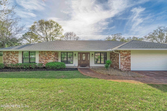 ranch-style home featuring decorative driveway, brick siding, a shingled roof, a front yard, and a garage