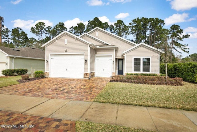 view of front of home featuring stone siding, a front lawn, decorative driveway, and an attached garage