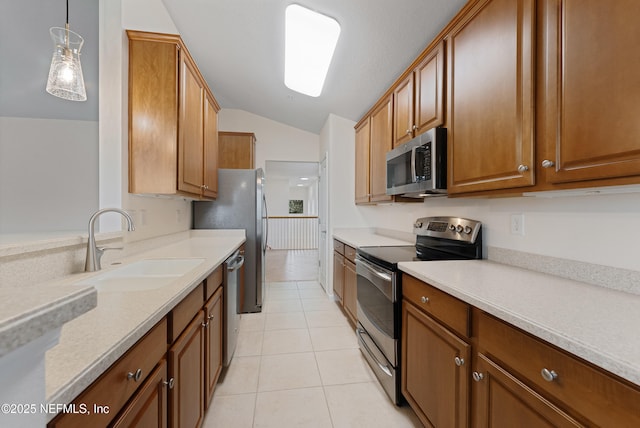 kitchen featuring light tile patterned floors, a sink, vaulted ceiling, light countertops, and appliances with stainless steel finishes