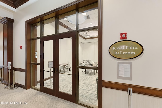 doorway featuring french doors, light carpet, and crown molding