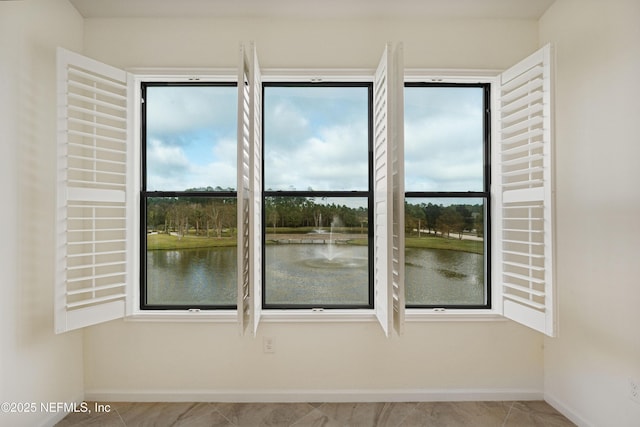 unfurnished room with a water view and baseboards