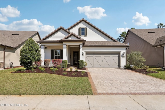 craftsman-style home with a front lawn, decorative driveway, and an attached garage