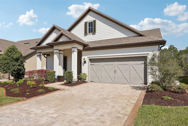 view of front of house with a shingled roof and decorative driveway