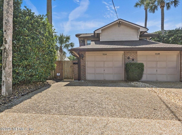 view of front of home featuring a garage, driveway, a shingled roof, fence, and brick siding