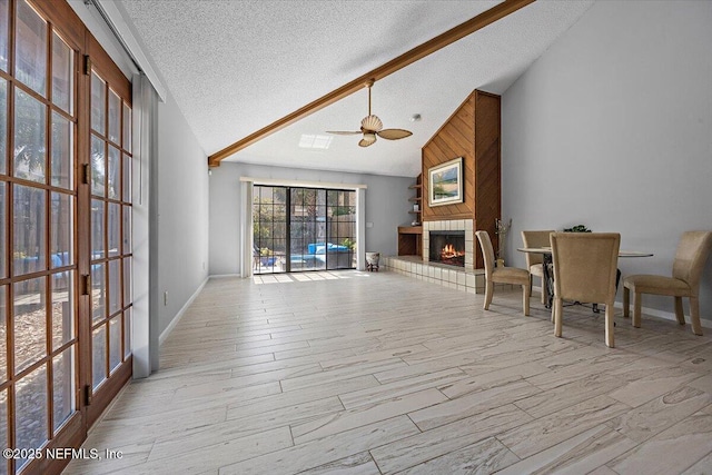 unfurnished living room with a ceiling fan, a textured ceiling, wood finished floors, high vaulted ceiling, and a tile fireplace