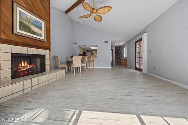 unfurnished living room featuring a tile fireplace, wood finished floors, baseboards, and stairs