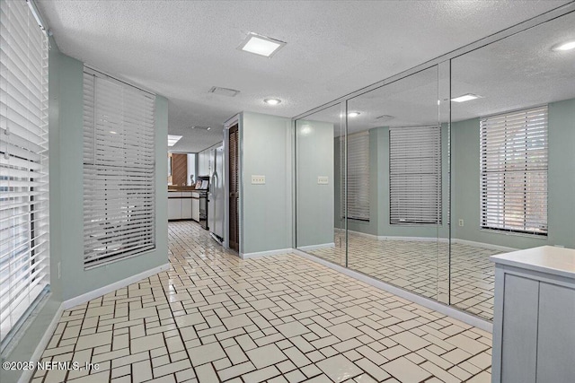 interior space featuring brick floor, baseboards, and a textured ceiling