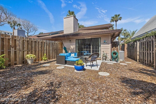 back of house with a fenced backyard, a chimney, an outdoor hangout area, and a patio