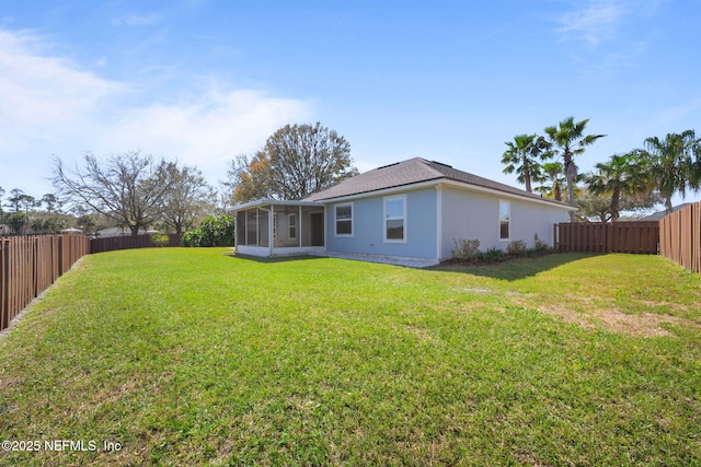 back of property with a yard, a fenced backyard, and a sunroom