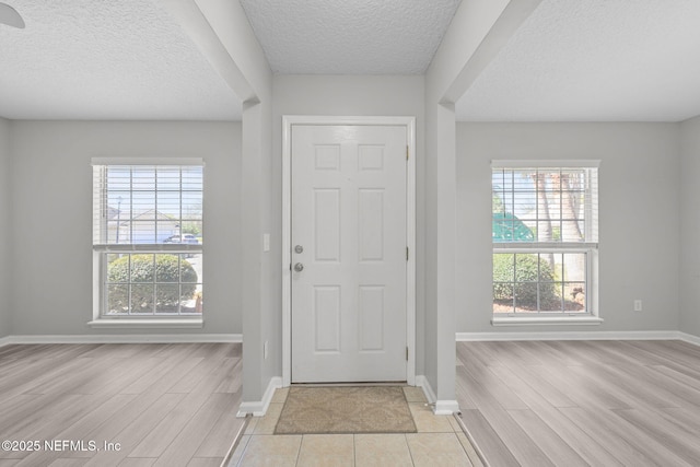 entrance foyer featuring light wood-style floors, baseboards, and a textured ceiling