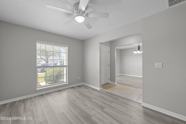 unfurnished room featuring visible vents, a textured ceiling, wood finished floors, baseboards, and ceiling fan with notable chandelier