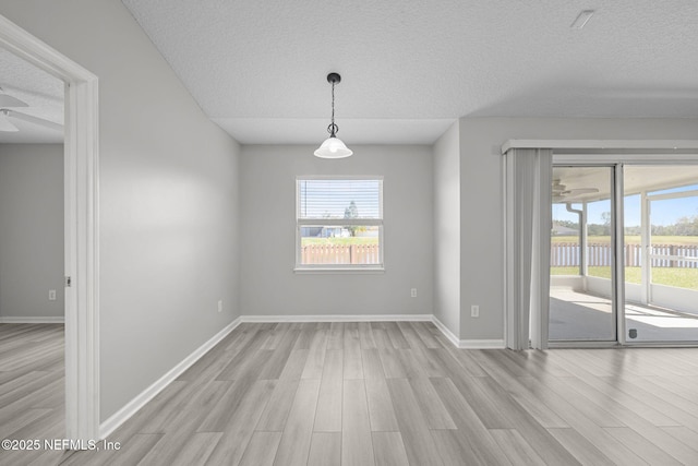 unfurnished dining area with a textured ceiling, baseboards, and wood finished floors