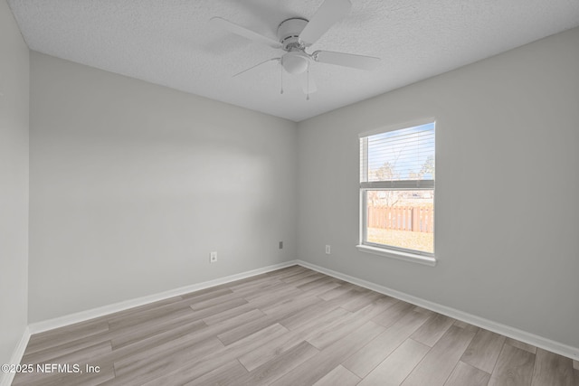 spare room with ceiling fan, a textured ceiling, light wood-style flooring, and baseboards