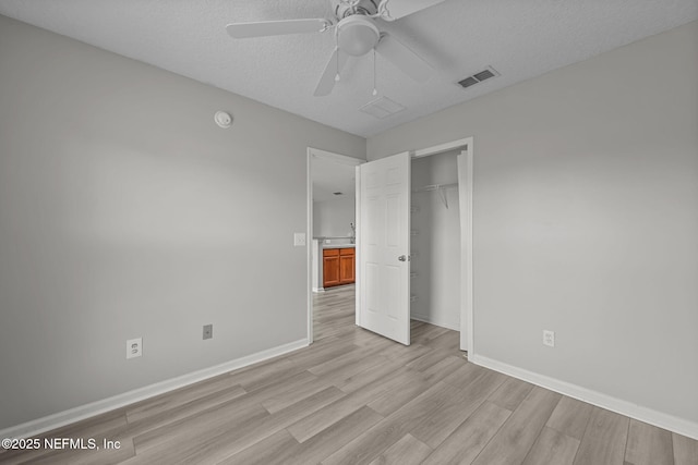 unfurnished bedroom with baseboards, a closet, visible vents, and light wood-style floors