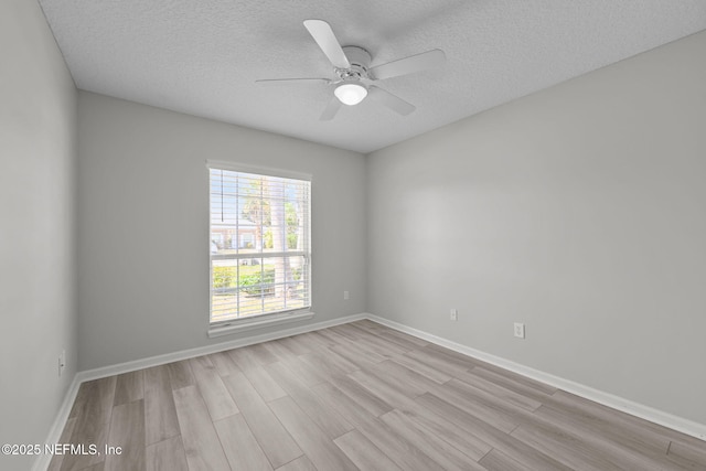 empty room with ceiling fan, a textured ceiling, wood finished floors, and baseboards