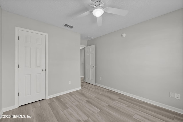 unfurnished bedroom featuring a textured ceiling, ceiling fan, visible vents, baseboards, and light wood-type flooring