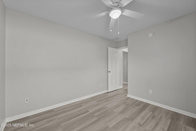 empty room with light wood finished floors, a textured ceiling, baseboards, and a ceiling fan