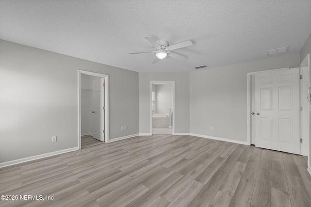 unfurnished bedroom featuring light wood finished floors, visible vents, and a walk in closet