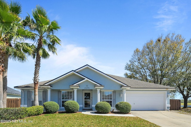 view of front of property featuring stucco siding, an attached garage, a front yard, fence, and driveway