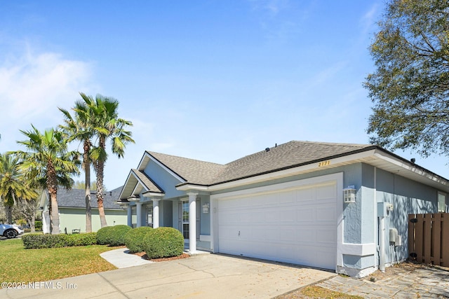 view of front of home with concrete driveway, roof with shingles, an attached garage, and stucco siding