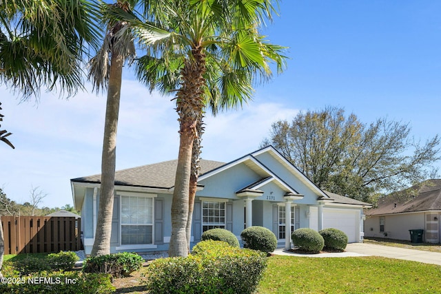 view of front facade featuring stucco siding, concrete driveway, a front yard, fence, and a garage