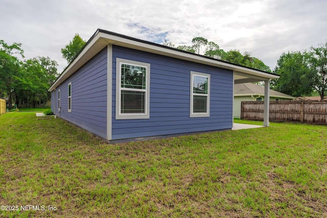 view of side of property featuring fence and a lawn