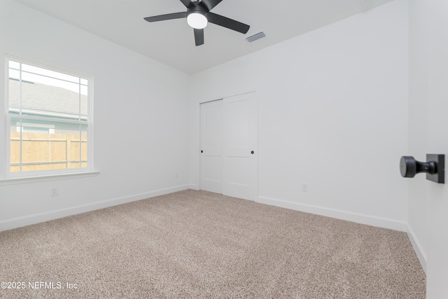 carpeted empty room featuring visible vents, ceiling fan, and baseboards