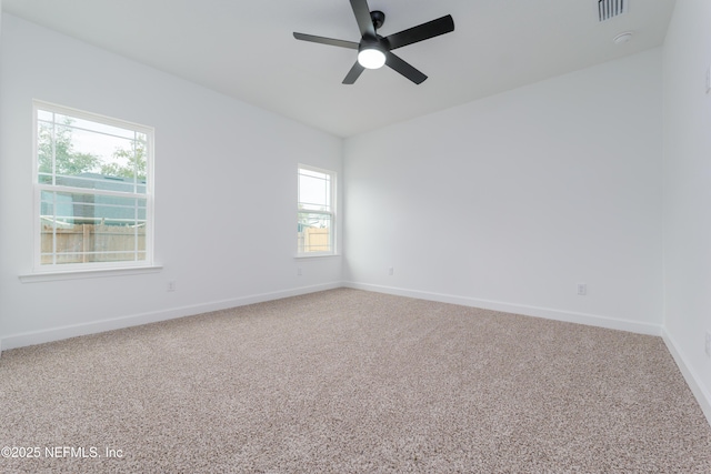 carpeted empty room featuring a ceiling fan, visible vents, and baseboards