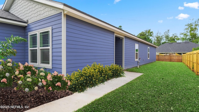 view of side of property featuring a lawn and fence