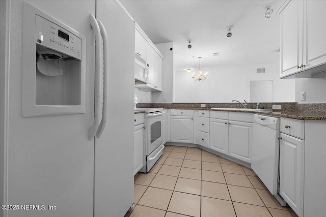 kitchen with white appliances, dark countertops, decorative light fixtures, white cabinetry, and light tile patterned flooring