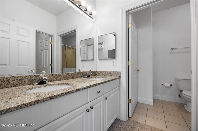 bathroom featuring toilet, tile patterned flooring, double vanity, and a sink