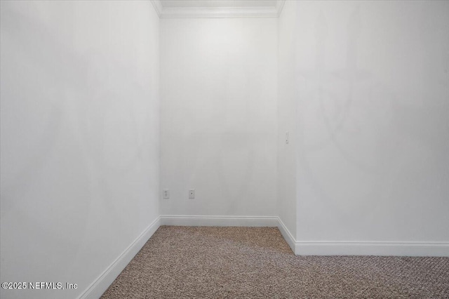 carpeted spare room featuring baseboards and crown molding