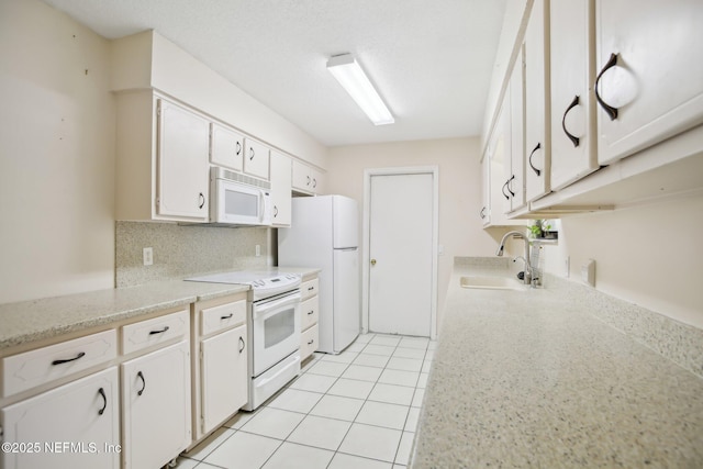 kitchen featuring white appliances, light tile patterned floors, white cabinets, light countertops, and a sink