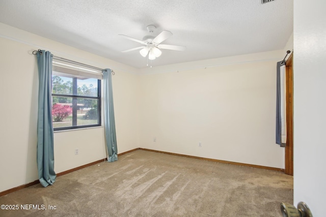 spare room featuring a ceiling fan, light carpet, a textured ceiling, and baseboards