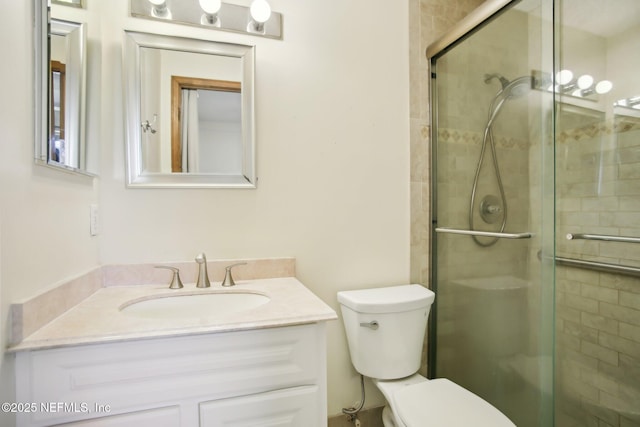 bathroom featuring toilet, a shower stall, and vanity