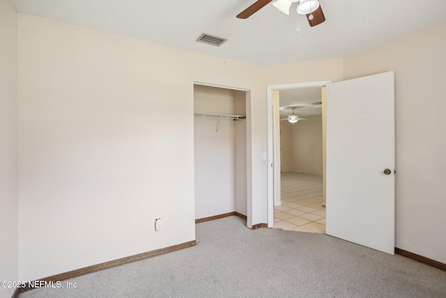 unfurnished bedroom featuring light colored carpet, visible vents, baseboards, a ceiling fan, and a closet