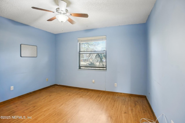 unfurnished room with a textured ceiling, wood finished floors, a ceiling fan, and baseboards