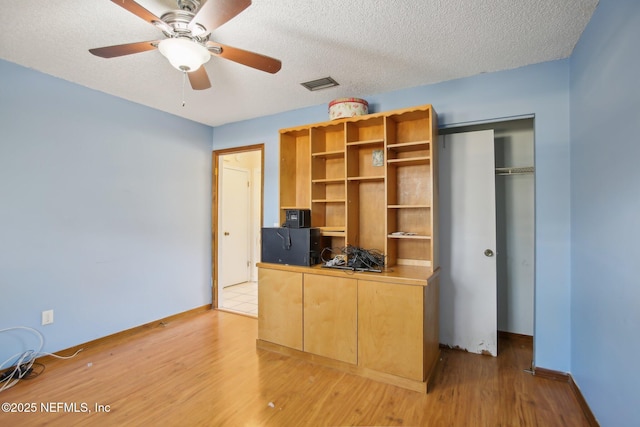 unfurnished office with light wood-type flooring, visible vents, and a textured ceiling