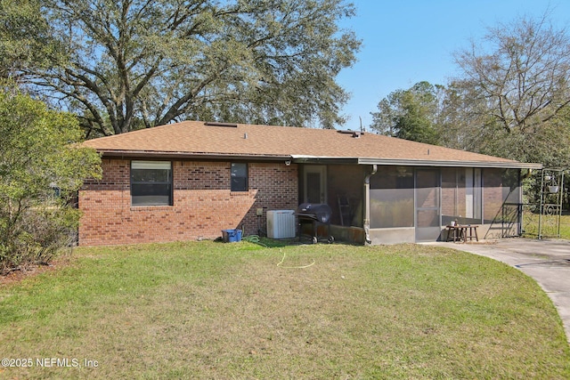 back of house featuring brick siding, a lawn, cooling unit, and a sunroom