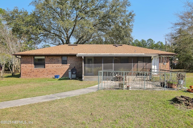 view of front of house with a patio area, a sunroom, brick siding, and a front lawn