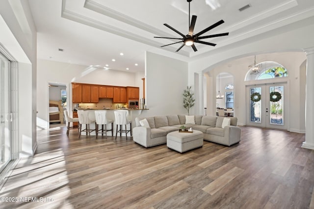 living room with ornate columns, visible vents, and a tray ceiling