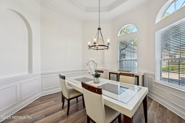 dining room with dark wood-style floors, ornamental molding, a raised ceiling, and a decorative wall