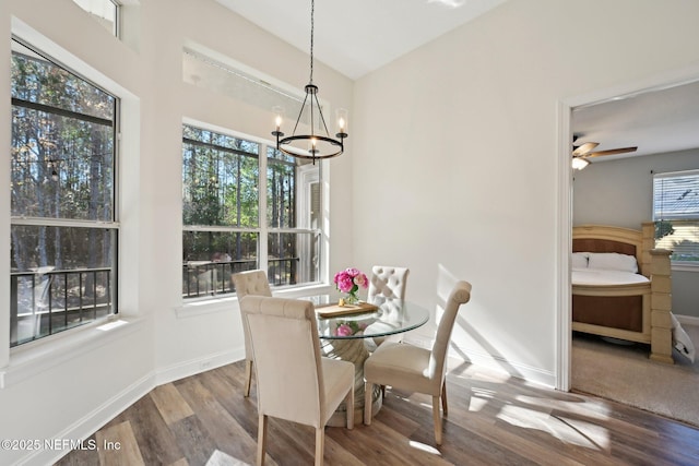 dining area with ceiling fan with notable chandelier, vaulted ceiling, baseboards, and wood finished floors