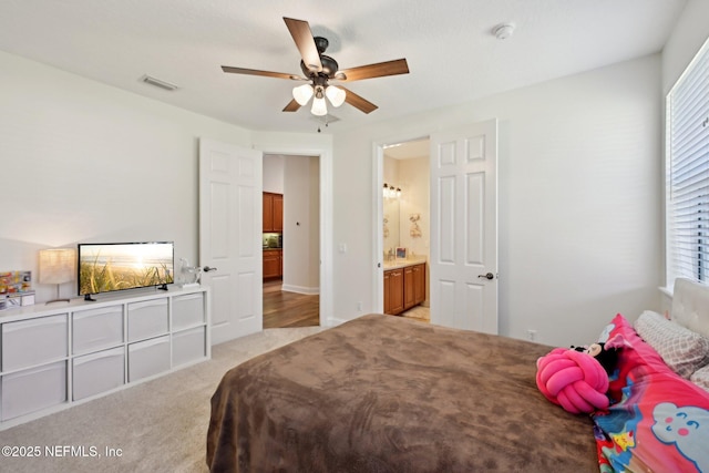 bedroom with a ceiling fan, visible vents, connected bathroom, and light carpet