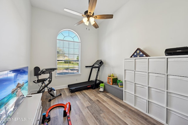 workout room with wood finished floors, a ceiling fan, and baseboards