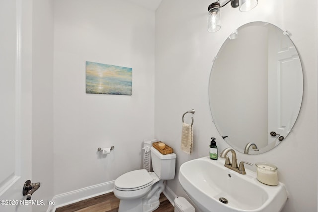 bathroom featuring baseboards, a sink, toilet, and wood finished floors