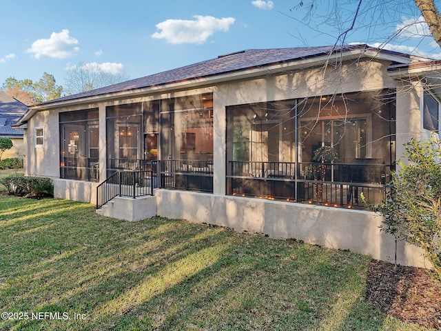 back of property with a sunroom, a lawn, and stucco siding