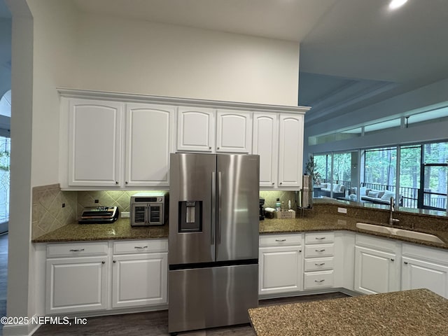 243 Stonewell Dr, Saint Johns, FL 32259 - kitchen featuring stainless steel fridge with ice dispenser, white cabinetry, dark stone counters, and decorative backsplash